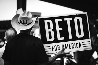 持有Beto for America标牌的人的灰度照片